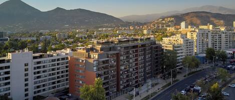Un paisaje urbano con edificios modernos, una carretera y montañas a lo lejos.