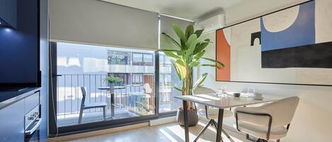 Una cocina moderna con un ventanal grande, una zona de comedor con mesa y sillas, y una planta en maceta.