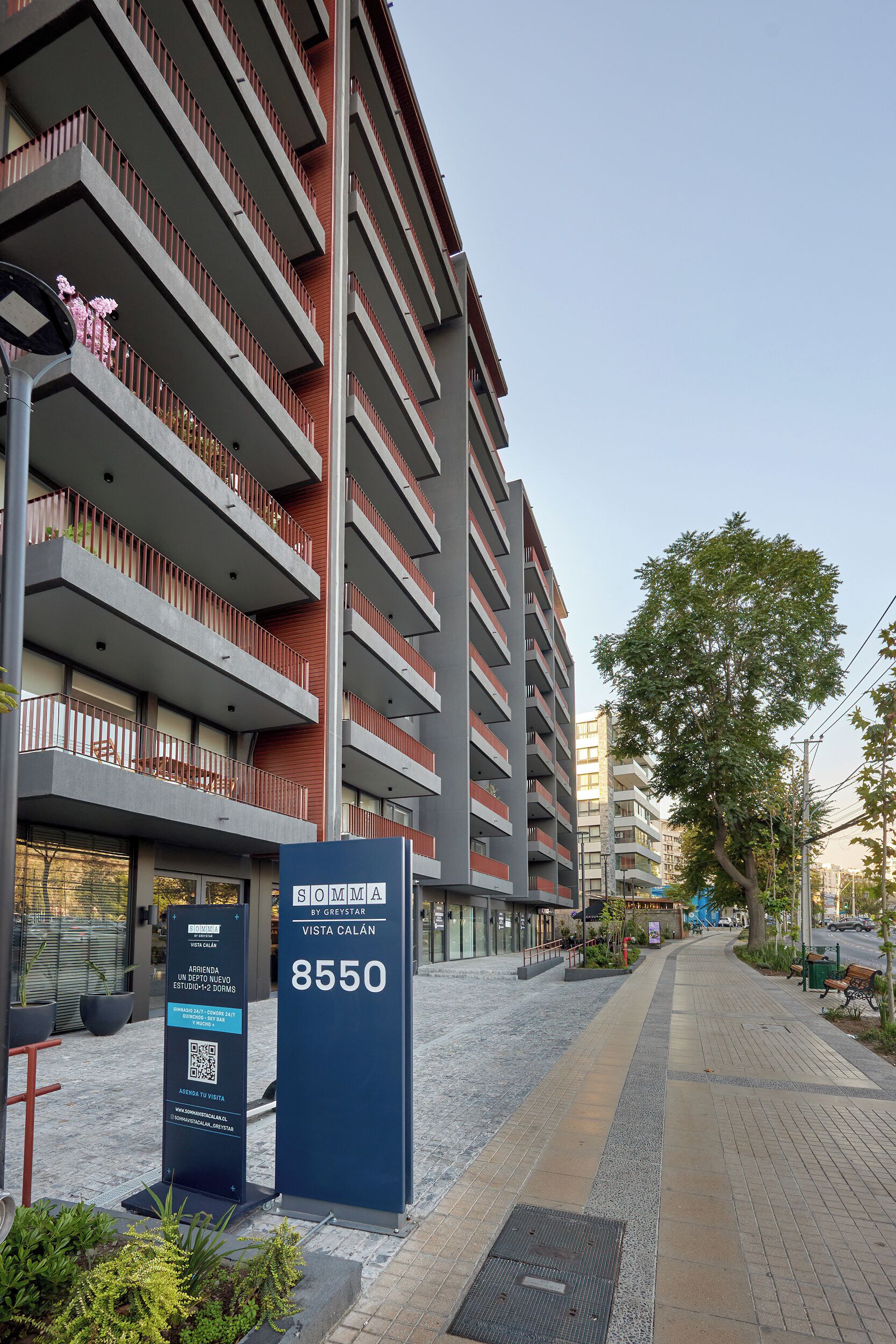En modern byggnad med flera balkonger, en skylt med texten ”VISTA CALAN 8550” och en QR-kod för ytterligare information.
