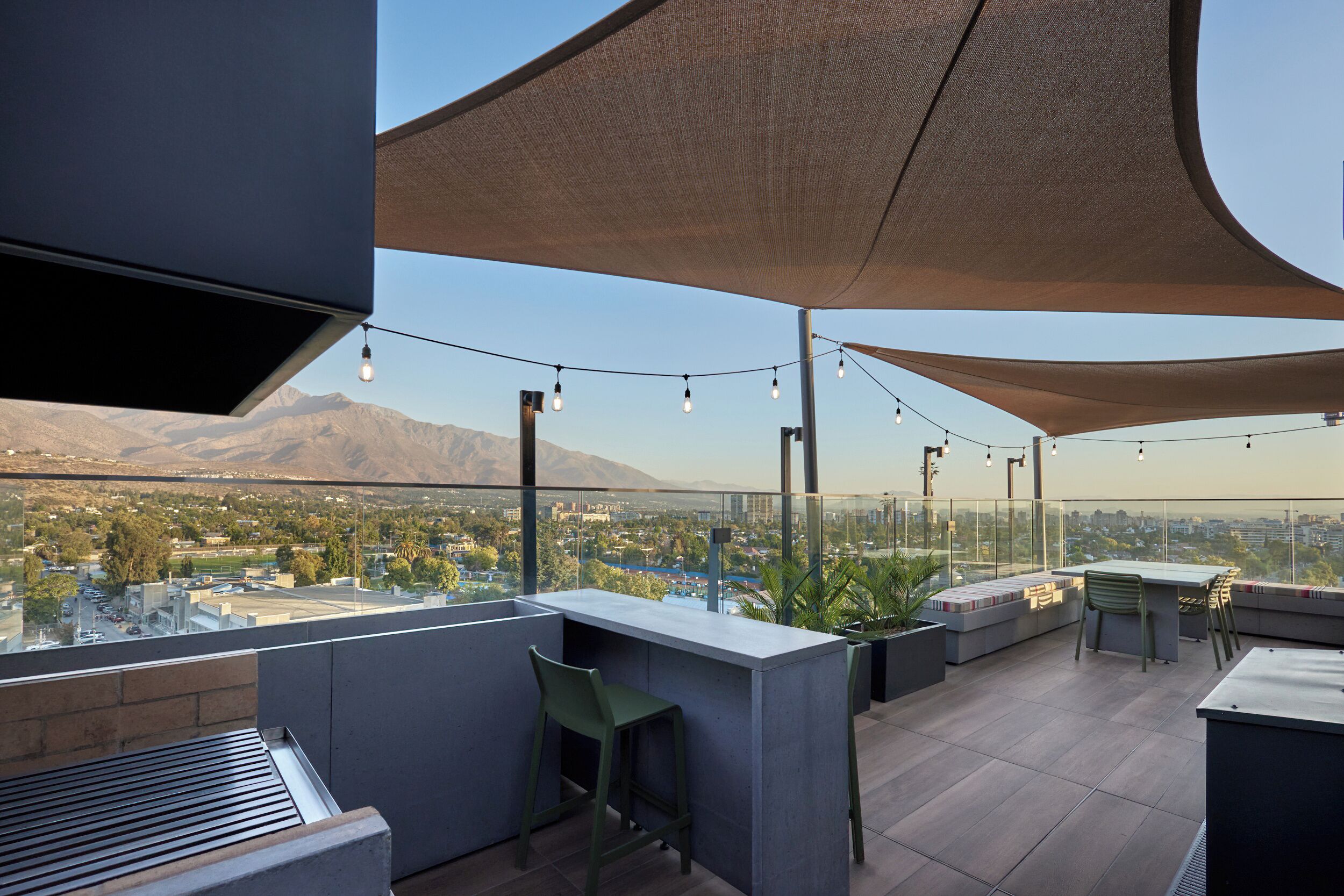 Terraza en la azotea con zona de bar, asientos y vistas a la ciudad y a las montañas.