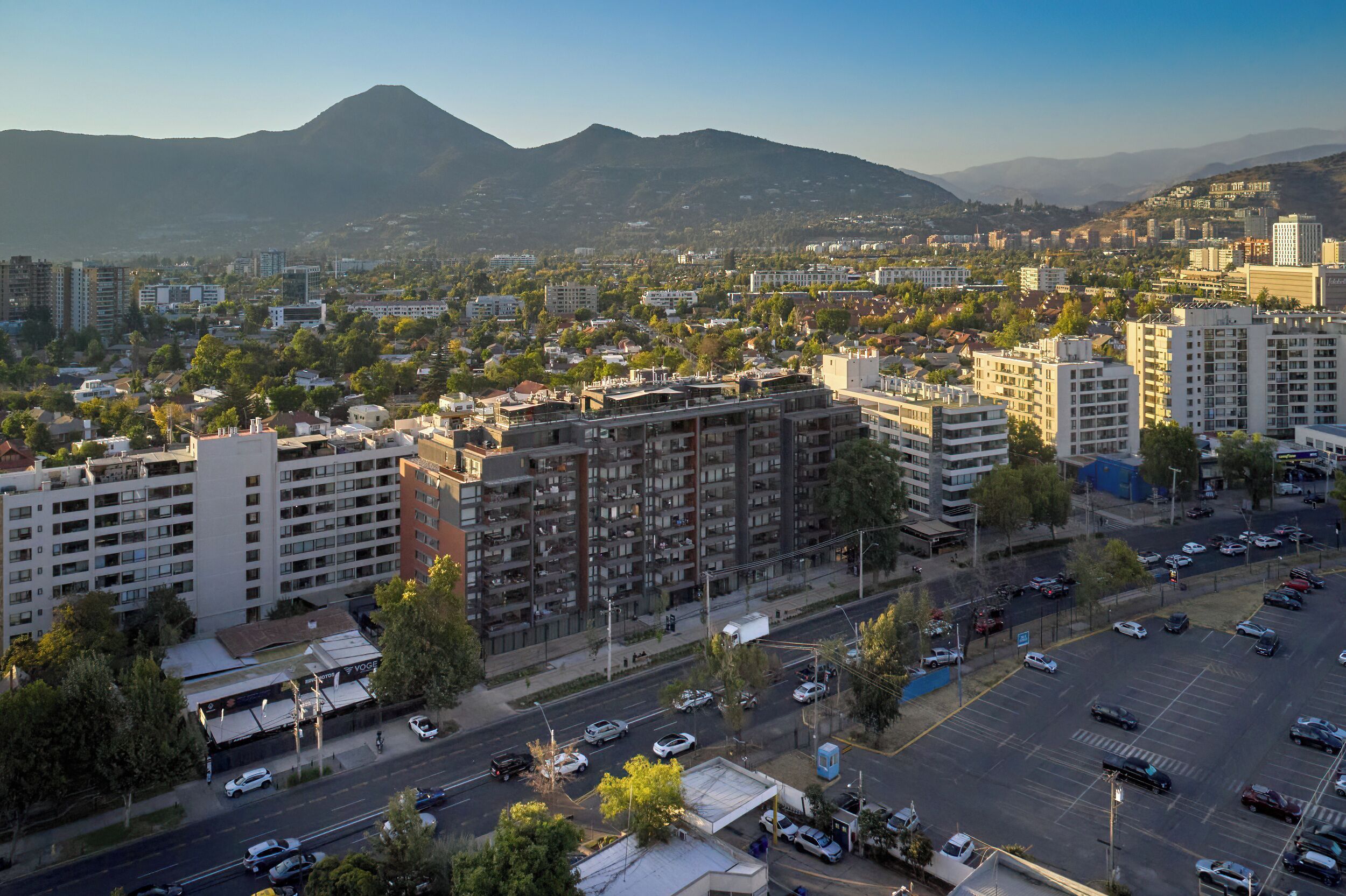 Un paisaje urbano con rascacielos, una carretera con coches y montañas al fondo.
