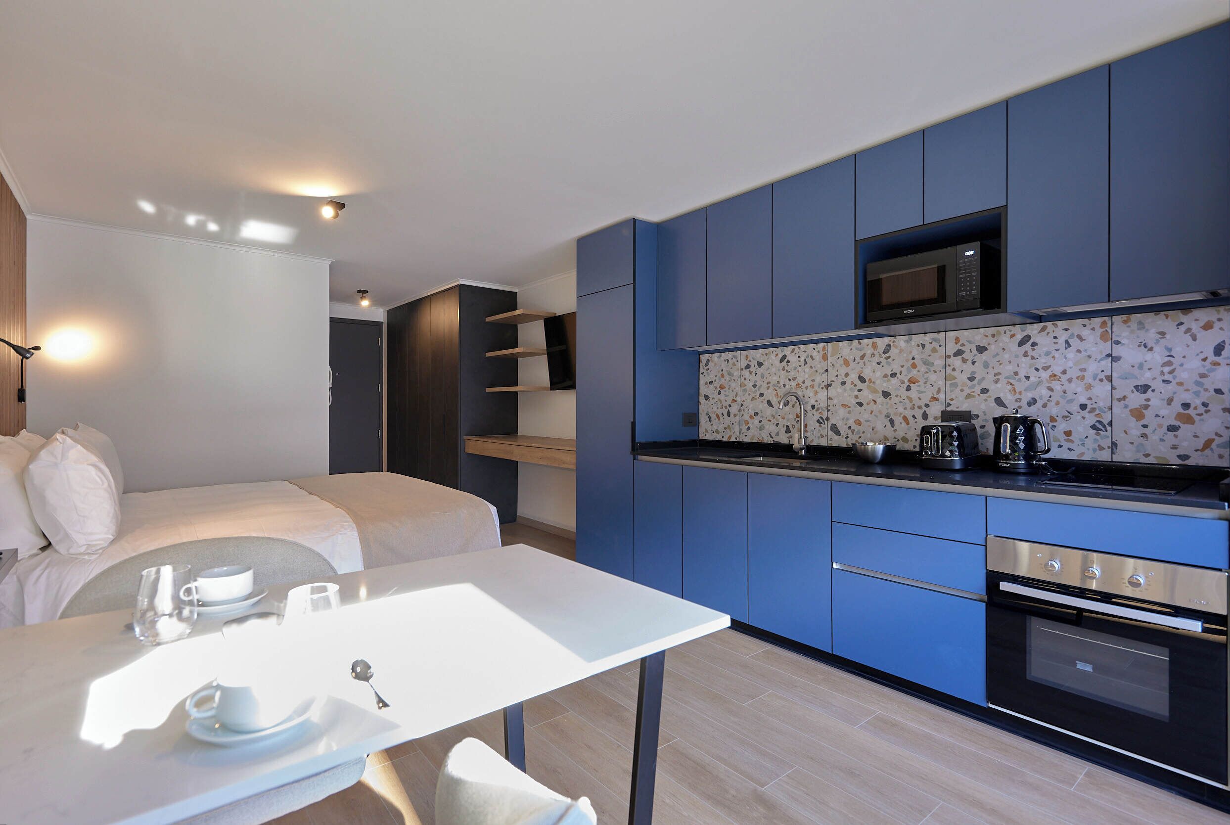 A modern kitchen with blue cabinets, a microwave, and a countertop with a coffee maker.