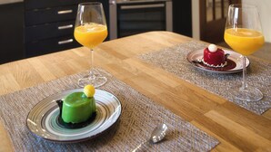Ett modernt kök med ett matbord för två personer, där det står uppdukat med en dessert och två glas apelsinjuice.