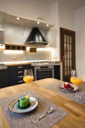 Une table à manger avec deux assiettes de nourriture et des verres de jus d’orange, dans une cuisine moderne.