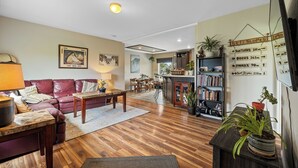 Een woonkamer met een houten vloer, een bank, een salontafel en een boekenplank.