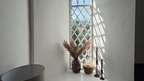 A bathroom with a white vanity, a window with a diamond pattern, and a vase with dried plants.
