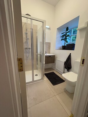 Driepersoonskamer, uitzicht op tuin | Badkamer | Een douche, een haardroger, handdoeken, toiletpapier