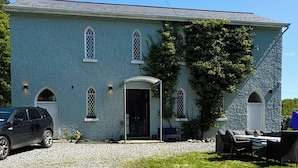 A large, single-story building with a stone facade, multiple arched windows, and a covered entrance.