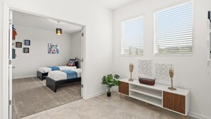 A bedroom with a bed, bedside tables, a plant, and artwork on the walls. - Stylish 3BR Condo Championsgate w Water Park (Davenport)