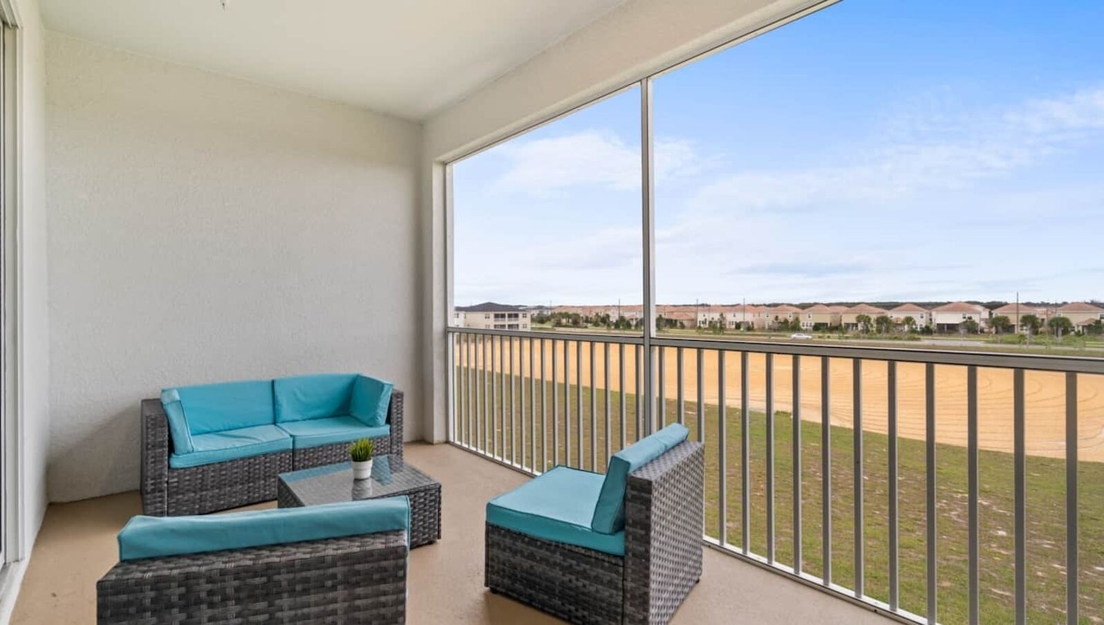 A balcony with wicker furniture and a view of a residential area.