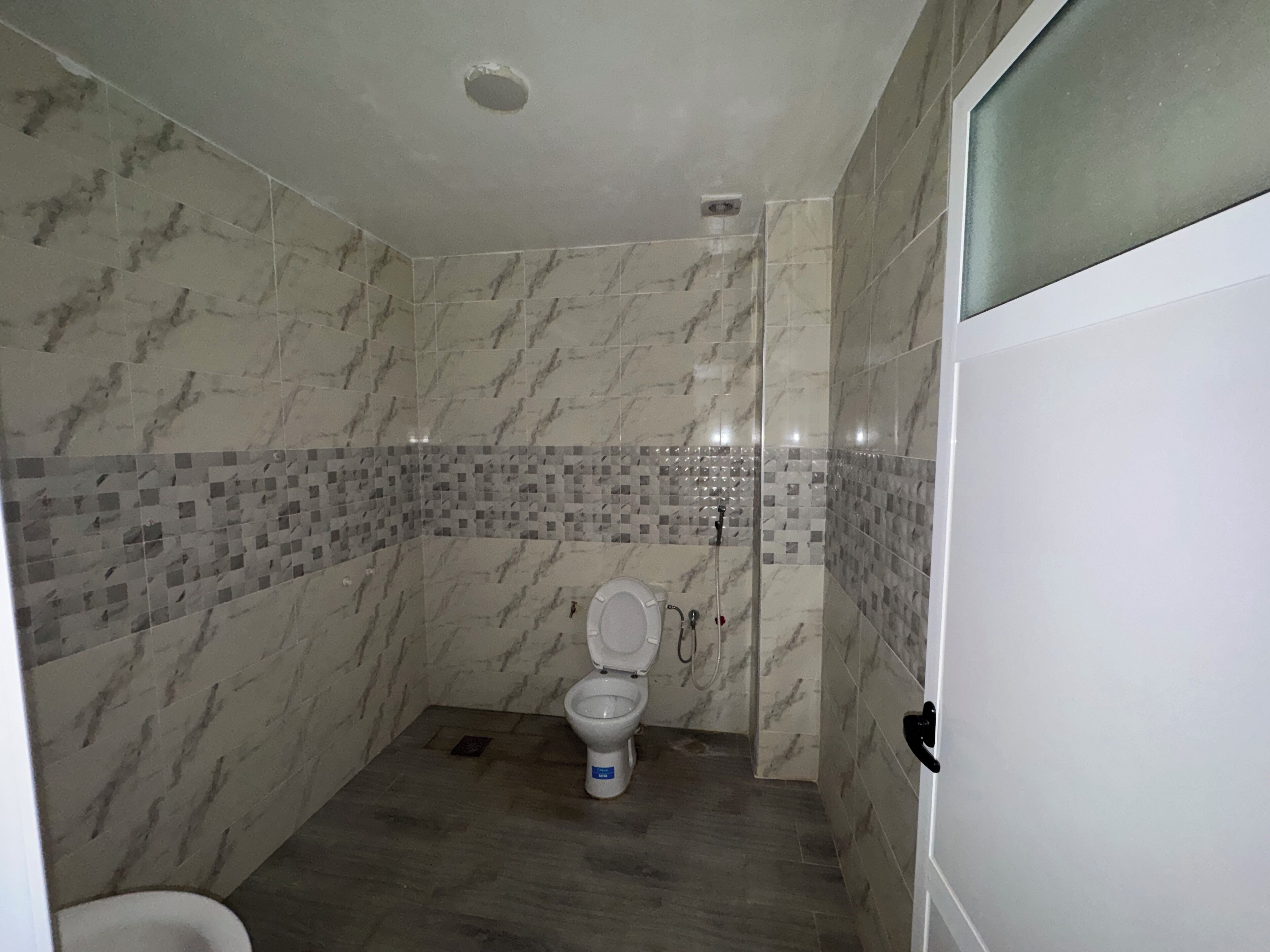 Ein Badezimmer mit Marmorwänden, einer gefliesten Duschkabine und einer Toilette.