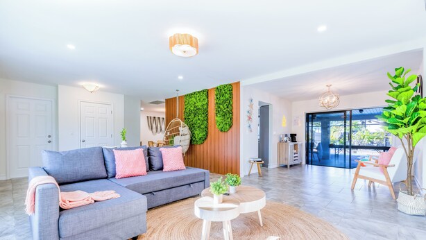 Ein modernes Wohnzimmer mit einem grauen Sofa, einem runden Couchtisch und einem großen Fenster.