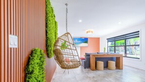Ein modernes Wohnzimmer mit einem Hängekorbstuhl, einer Couch, einem Holztisch und einem großen Fenster mit Blick.