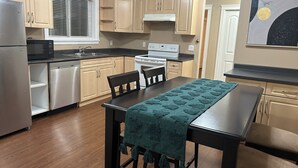 A compact kitchen with wooden cabinets, a stainless steel refrigerator, a microwave, a stove, and a dishwasher.