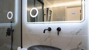 Ein modernes Badezimmer mit großem Spiegel, einem Vessel-Waschbecken und einer Handbrause.