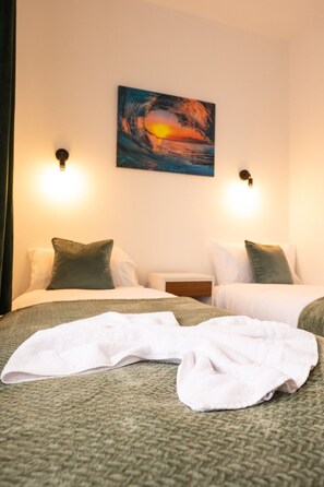 Ein Hotelzimmer mit zwei Betten, einem Bild an der Wand und zwei Wandleuchten.