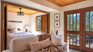 A bedroom with a large bed, a sofa, and a wooden door with glass panels. - Prime Sequoia Stay: Pool • Hot Tub • Sauna • Views (Three Rivers)