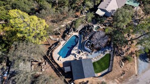 An aerial view of a residential area with a swimming pool, a covered patio, and a fenced yard. - Prime Sequoia Stay: Pool • Hot Tub • Sauna • Views (Three Rivers)
