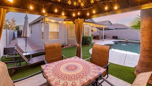 A covered patio area with a pool, outdoor furniture, and string lights. - Private Pool & Patio: Home in Surprise! (Surprise)