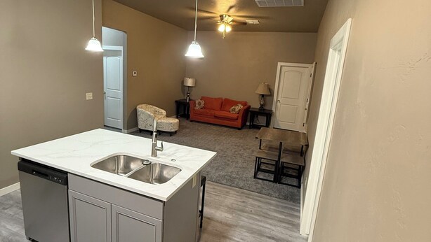 A compact kitchen with a central island, built-in dishwasher, and a ceiling fan.