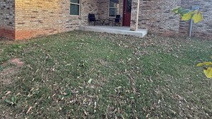 A brick house with a covered patio, a door, and a window.