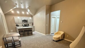 A spacious living area with a kitchen in the background, a ceiling fan, and a staircase leading to another level.
