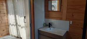 Ein Badezimmer mit Holzwand, Waschbecken und Spiegel.