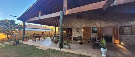 A covered outdoor patio area with brick walls, wooden furniture, and potted plants.