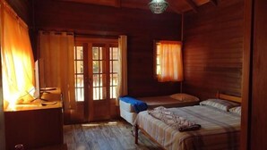 Ein Zimmer in einer Holzhütte mit einem Bett, einem Schreibtisch und einem Fenster mit Vorhängen.