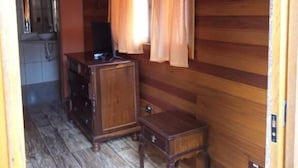 Ein Holzhütten-Innenraum mit einer Küchenzeile, einem Holzkabinett, einem kleinen Tisch und einem Fenster mit Vorhängen.