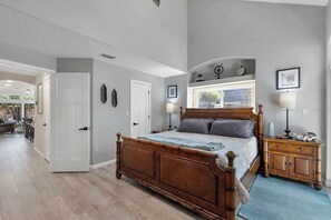 Une chambre à coucher avec un lit en bois, une table de chevet, une fenêtre donnant sur un beau paysage et une porte menant à une autre pièce.