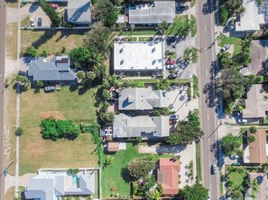 Une vue aérienne d’un quartier résidentiel comprenant plusieurs maisons, un espace ouvert central et de la végétation environnante.