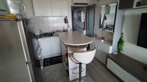 A modern kitchen with white cabinets, a central island with bar stools, a refrigerator, and a microwave. - Apartment T2 45M2 exceptional view Fitted kitchen shower room living room loggia (Agde)