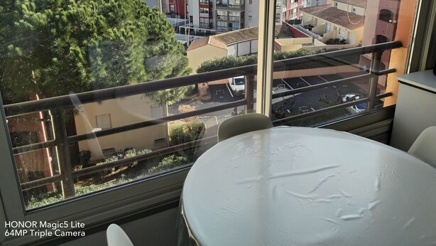 A hotel room with a balcony overlooking a cityscape, including a Ferris wheel and buildings. - Apartment T2 45M2 exceptional view Fitted kitchen shower room living room loggia (Agde)