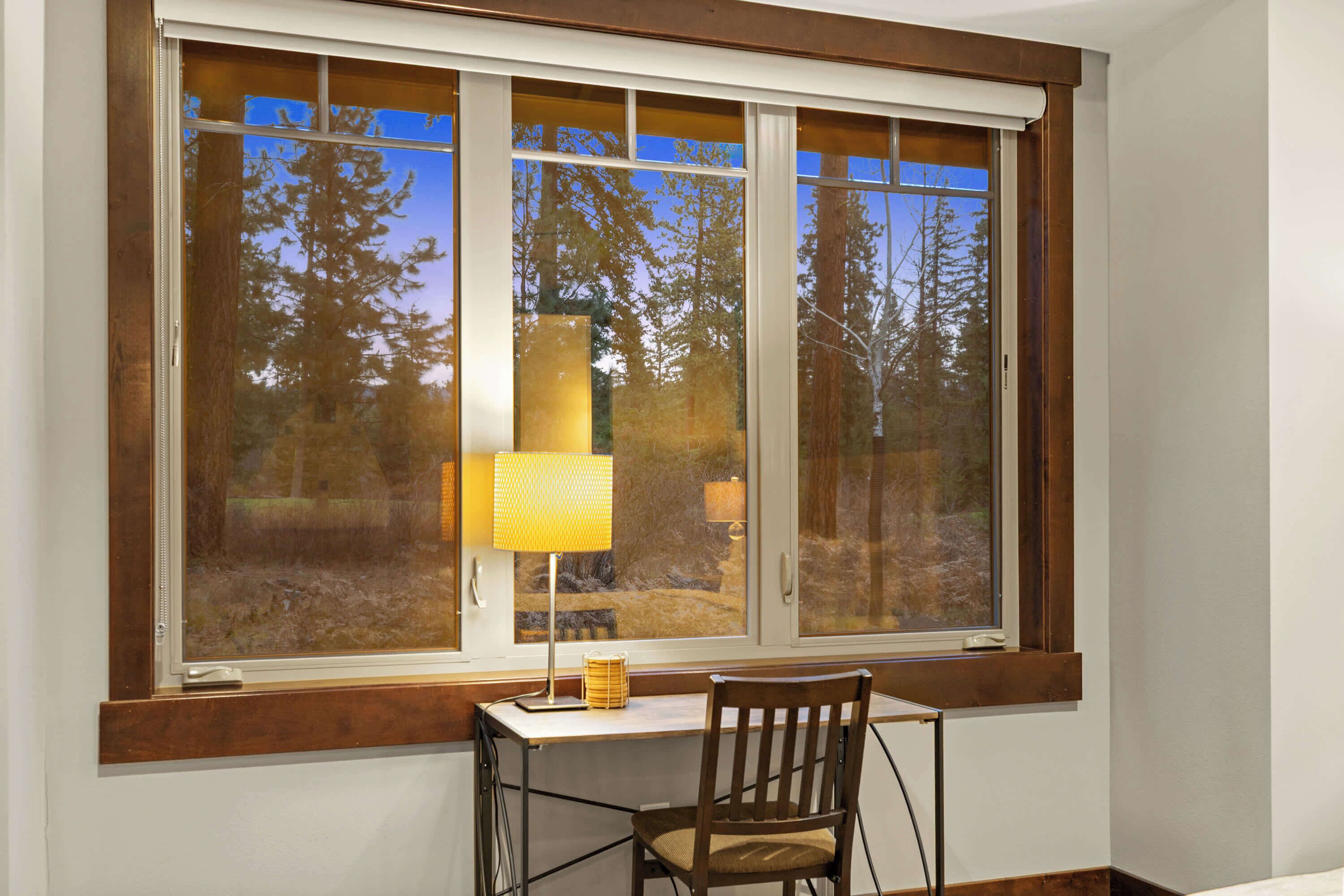 A room with a large window, a desk, and a chair.