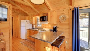 Une cuisine rustique, aménagée dans une cabane en bois, comprenant un réfrigérateur, une cuisinière, un four à micro-ondes et un grand îlot central avec des sièges.