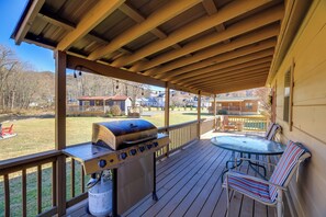 Une terrasse couverte avec un barbecue, des sièges d’extérieur et une vue sur les maisons au loin.