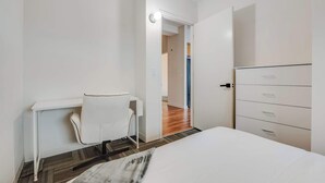 A modern hotel room with a bed, a desk, and a wardrobe.