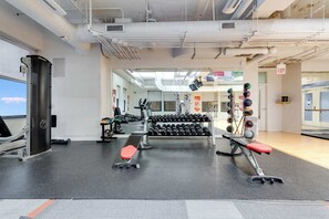 Ein Fitnessstudio mit Trainingsgeräten, Gewichten und Bänken.