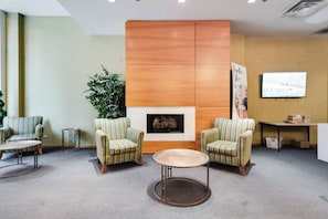 A lobby with two armchairs, a round table, a fireplace, a plant, and a television screen. - Downtown Chicago Stay with Free In & Out Parking 3 (Chicago)