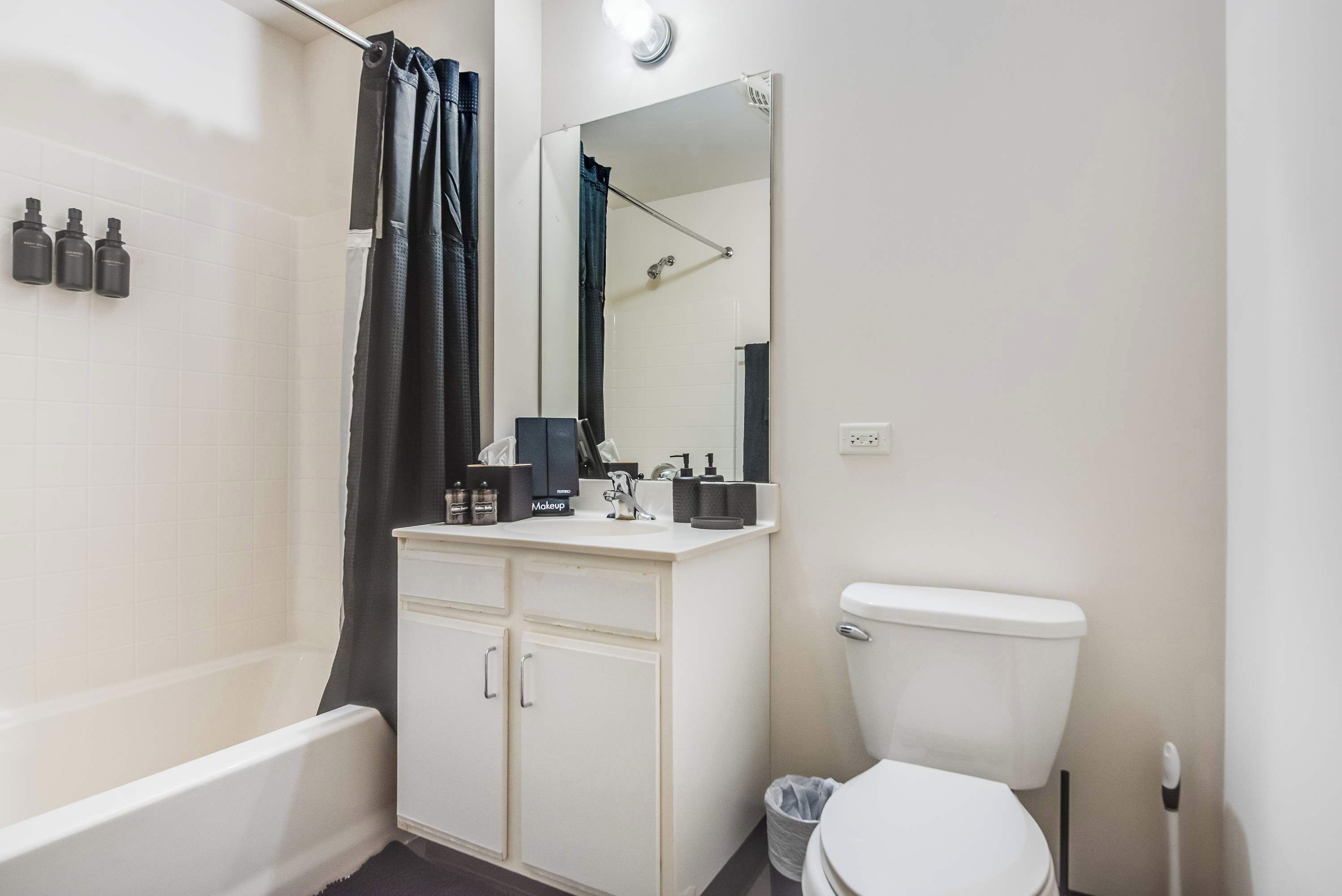 Ein Badezimmer mit Badewanne, Toilette, Waschtisch mit Spiegel und Duschvorhang.