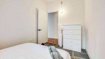Ein Hotelzimmer mit einem Bett, einer weißen Kommode und einer Tür zu einem weiteren Raum.
