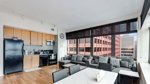 A modern apartment with a kitchen, dining area, and living room. It features large windows, a black refrigerator, and a grey sofa set. - Downtown Chicago Stay with Free In & Out Parking 5 (Chicago)