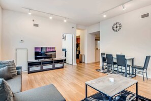 A modern living room with a sofa, TV, and a dining area with chairs and a table. - Downtown Chicago Stay with Free In & Out Parking 1 (Chicago)