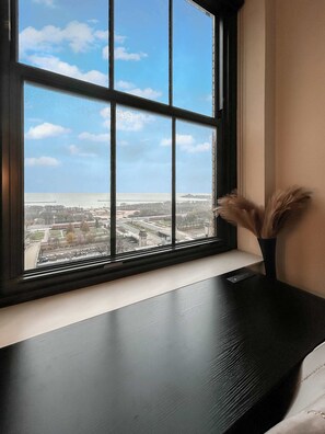 A window with a view of a cityscape, a black desk, and a vase with dried plants. - Downtown Chicago Stay with Free In & Out Parking 1 (Chicago)