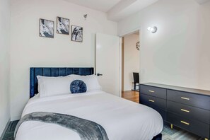 A bedroom with a large bed, a dark headboard, a dresser with gold handles, and two abstract paintings on the wall. - Downtown Chicago Stay with Free In & Out Parking 1 (Chicago)