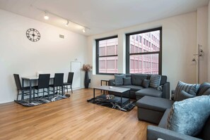 Un salon moderne avec un coin repas, de grandes fenêtres et une horloge au mur.