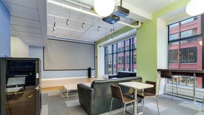 A modern conference room with a large screen, a sofa, and a table with chairs. - Downtown Chicago Stay with Free In & Out Parking 6 (Chicago)