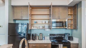 A modern kitchen with a stainless steel refrigerator, a microwave, a stove, and open shelving with dishes and cups. - Downtown Chicago Stay with Free In & Out Parking 6 (Chicago)