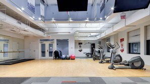 Un gimnasio espacioso con equipamiento de ejercicio, espejos y suelo de madera.